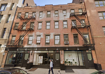 New York apartment for rent - A man is walking in front of a store with a black car parked in front of it.