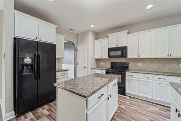 Jacksonville house for rent - A kitchen with black and white cabinets and a granite countertop.