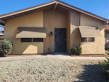 Hemet house for rent - A tan house with a black door and two windows.