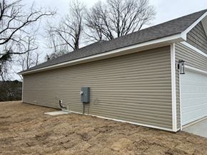 Benton house for rent - A garage with a grey roof and a white door is situated in a field.