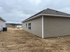 Benton house for rent - A single-story house with a grey siding and a brown roof is situated in a field.