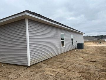 Benton house for rent - A small, single-story building with a grey siding and a white trim is situated in a dry, brown field.