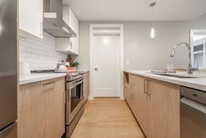 Victoria apartment for rent - A modern kitchen with wooden cabinets and stainless steel appliances.