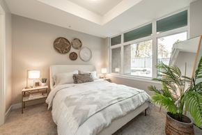 Victoria apartment for rent - A bedroom with a large bed, a potted plant, and a wall decorated with circular plates.