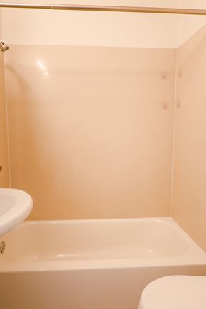 Oakland apartment for rent - A white bathtub sits in a bathroom with a toilet in the corner.