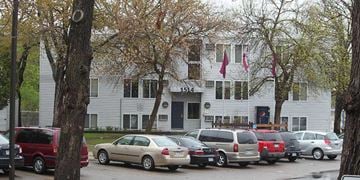 St Cloud apartment for rent - A white building with a black door and windows is surrounded by parked cars.