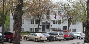 St Cloud apartment for rent - A white building with a black door and windows is surrounded by parked cars.