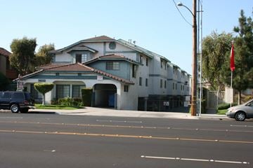 Anaheim apartment for rent - A grey building with a red roof and a flag on top.