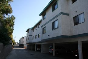 Anaheim apartment for rent - A street view of a residential area with apartment buildings and cars parked in the garage.