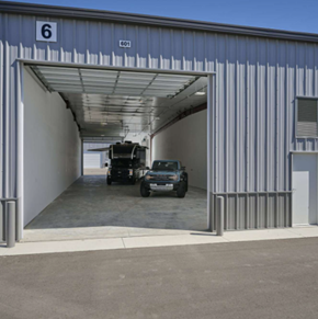 Boise apartment for rent - A blue building with the number 6 on it has a white truck and a black jeep parked in it.