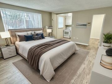 Aurora apartment for rent - A bedroom with a large bed and a small kitchenette in the background.