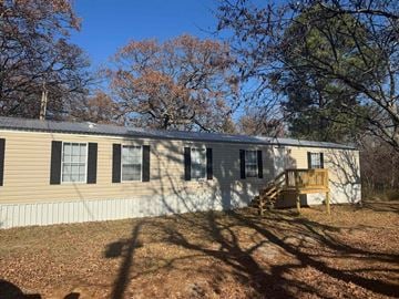 Norman house for rent - A house with a porch and a tree in front.