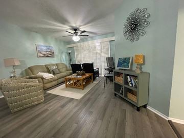 Fort Myers house for rent - A living room with a ceiling fan and a painting on the wall.
