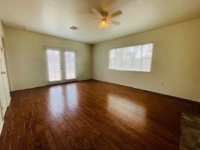 Las Cruces house for rent - A room with wooden floors and a ceiling fan.