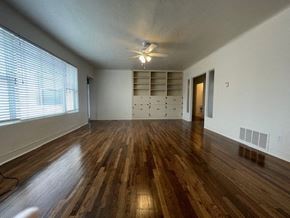 Las Cruces house for rent - A room with wooden floors and a ceiling fan.