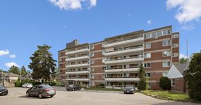 Kitchener apartment for rent - A large brick building with a parking lot in front.