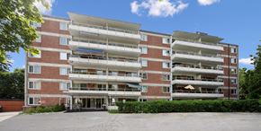 Kitchener apartment for rent - A large red brick building with a parking lot in front.