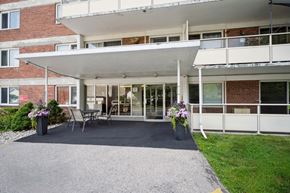 Kitchener apartment for rent - A white building with a balcony and a gravel driveway.