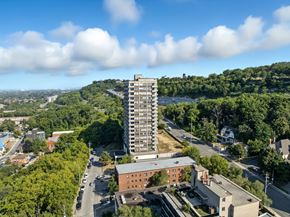 Hamilton apartment for rent - A tall building stands in the middle of a green landscape.
