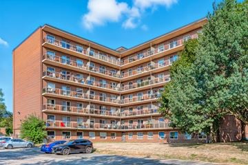 Burlington apartment for rent - A large apartment building with a blue car parked in front.