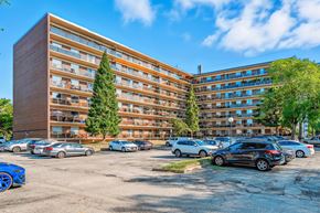 Burlington apartment for rent - A parking lot with cars and a large building in the background.