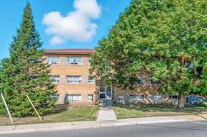 Burlington apartment for rent - A building with a brown facade is surrounded by green trees.