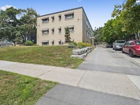 Barrie apartment for rent - A beige building with a green lawn in front.