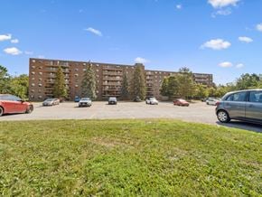 Barrie apartment for rent - A parking lot with cars and apartment buildings in the background.