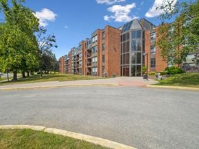 Barrie apartment for rent - A large red brick building with a glass entrance and a tree in front.