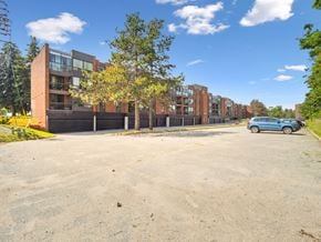 Barrie apartment for rent - A blue car is parked in a parking lot in front of a building.