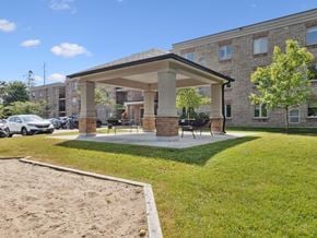 Barrie apartment for rent - A sandbox is located in front of a building with a covered patio.