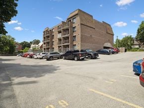 Orillia apartment for rent - A parking lot with cars and a building in the background.