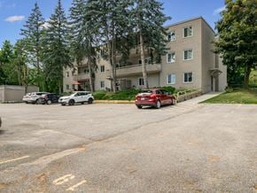 Orillia apartment for rent - A parking lot with cars and a building in the background.