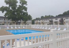 Monroe apartment for rent - A pool surrounded by white chairs and a white fence.