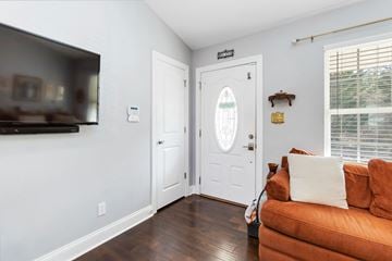 Belmont house for rent - A living room with a brown couch and a flat screen TV mounted on the wall.