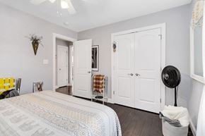 Belmont house for rent - A bedroom with a bed, two doors, and a fan.