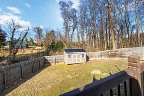 Belmont house for rent - A small house is surrounded by a fence in a grassy backyard.