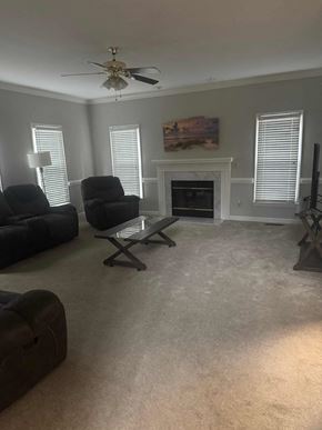 Kernersville house for rent - A living room with a fireplace, two chairs, and a ceiling fan.