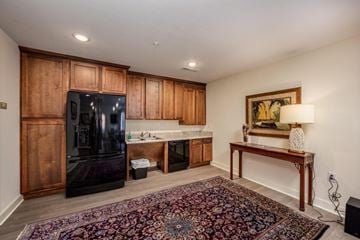 Statesville apartment for rent - A black fridge sits in a kitchen with wooden cabinets and a rug on the floor.