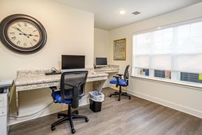 Statesville apartment for rent - A room with a desk, chairs, and a clock on the wall.