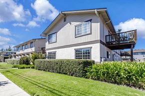 Redwood City apartment for rent - A house with a balcony and a well-manicured lawn.