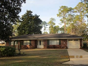 Bainbridge house for rent - A house with a brick facade and a white garage door is surrounded by trees.