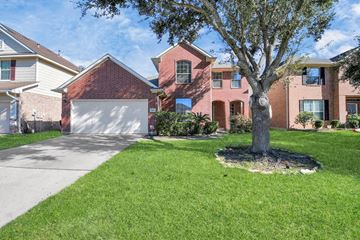Houston house for rent - A tree in a grassy area in front of a red brick house.