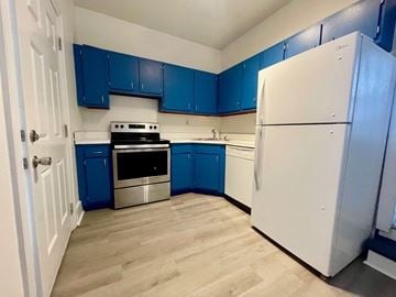 Louisville apartment for rent - A kitchen with blue cabinets and a white refrigerator.