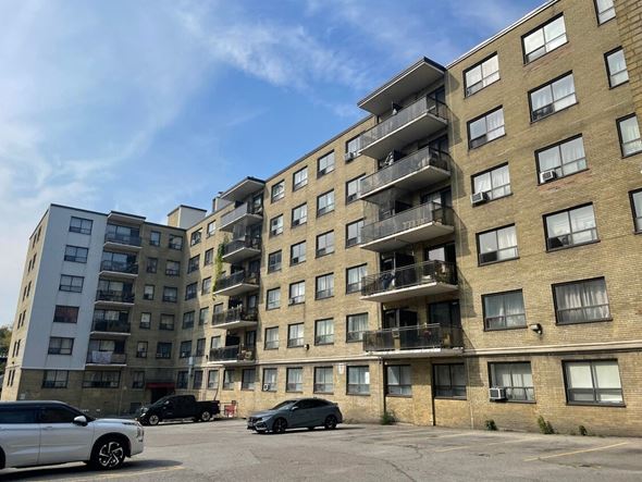 Toronto apartment for rent - A white car is parked in front of a building with a balcony.