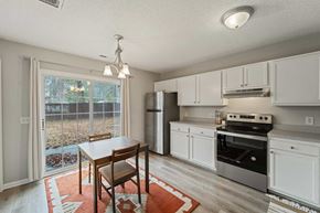 Jacksonville house for rent - A kitchen with white cabinets and a wooden table.