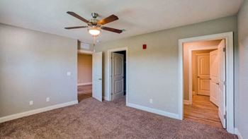 A room with a ceiling fan and carpeted floor.