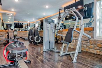 A gym with a variety of equipment including a leg press machine and a cable machine.