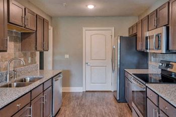 A kitchen with brown cabinets and a black refrigerator.