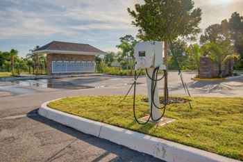 A charging station for electric vehicles is located in a grassy area in front of a house.